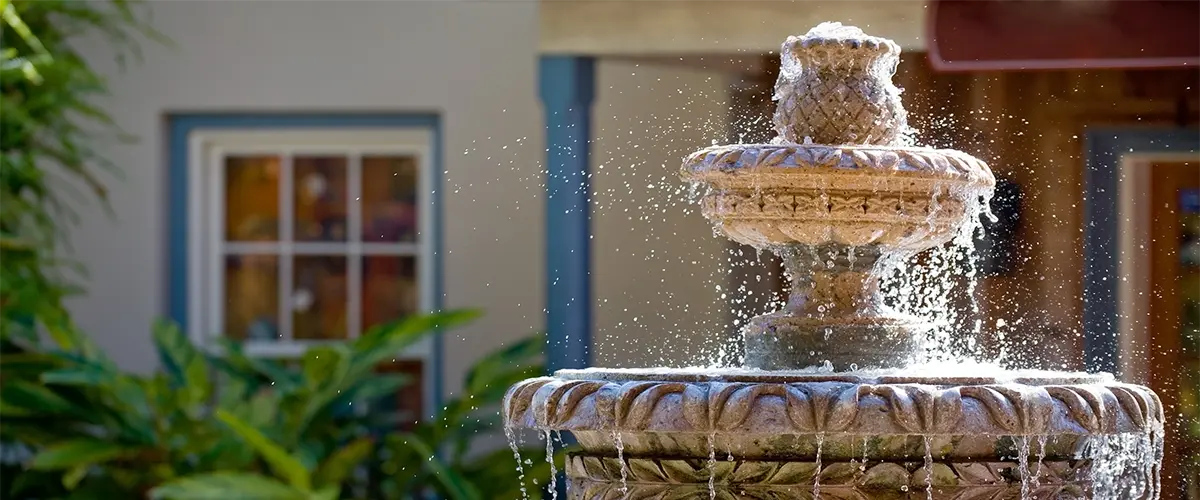 Decorative tiered fountain with water splashing in sunlight