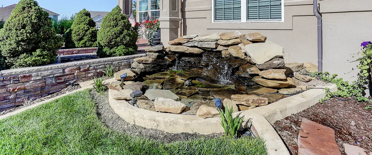 Small backyard pond with stacked stone waterfall feature