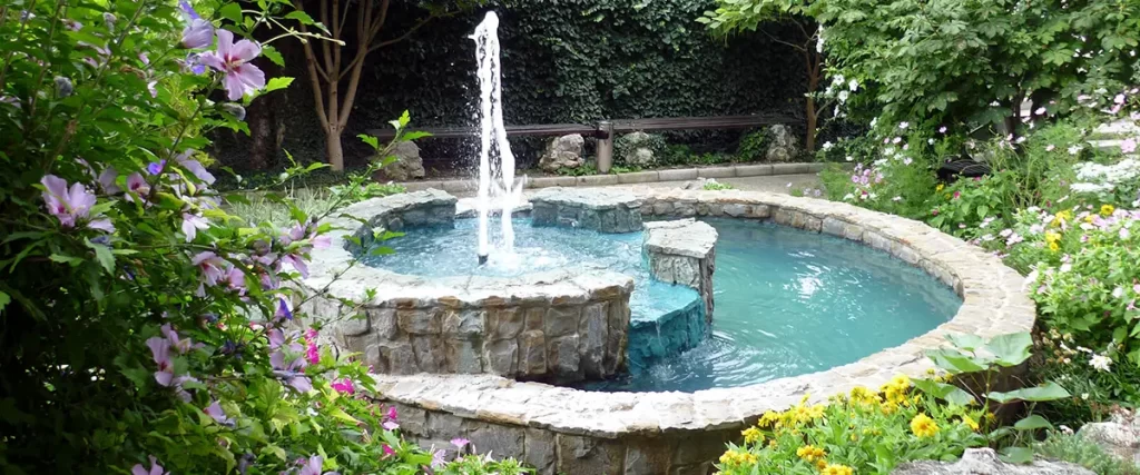 Circular stone fountain surrounded by flowers