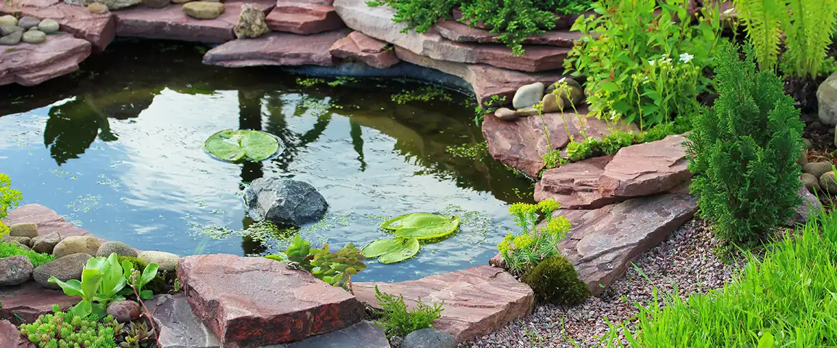 Small garden pond with red stone border