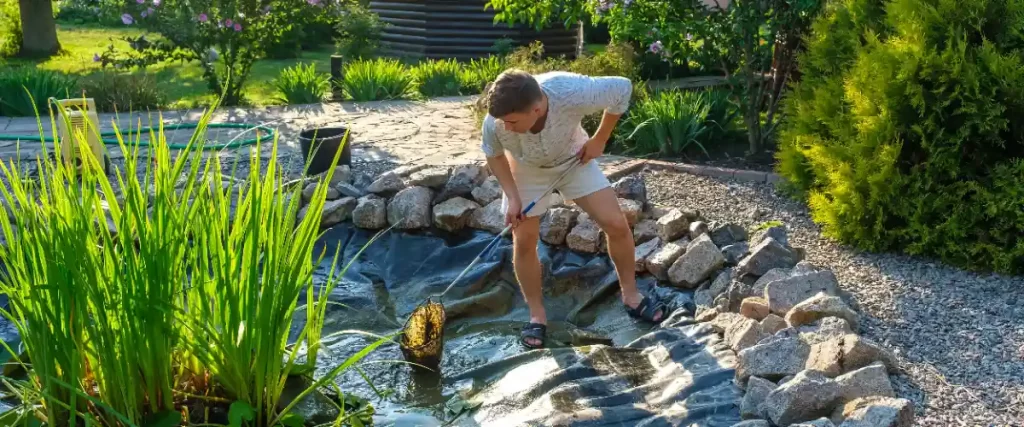 a person performing maintenance on a garden pond