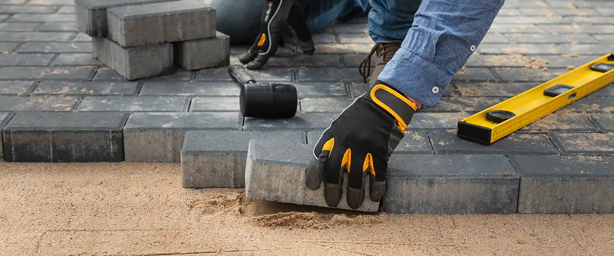 worker laying pavers on sand base