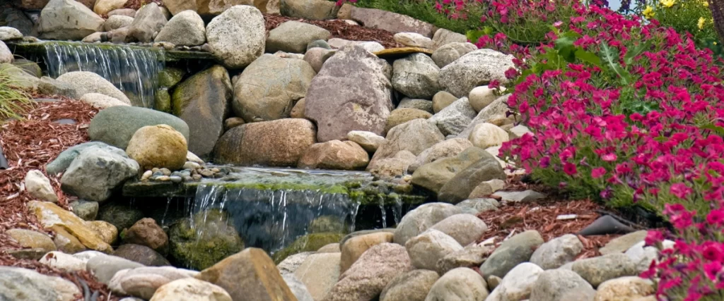 Pondless waterfall with layered rocks and cascading water in a landscaped garden