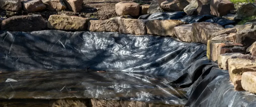 A close-up view of the heavy-duty liner being installed inside the pond basin.