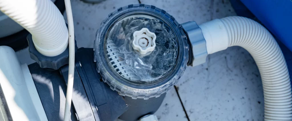 A top-down view of a mechanical pond filtration pump with a clear lid showing active water circulation and debris collection.