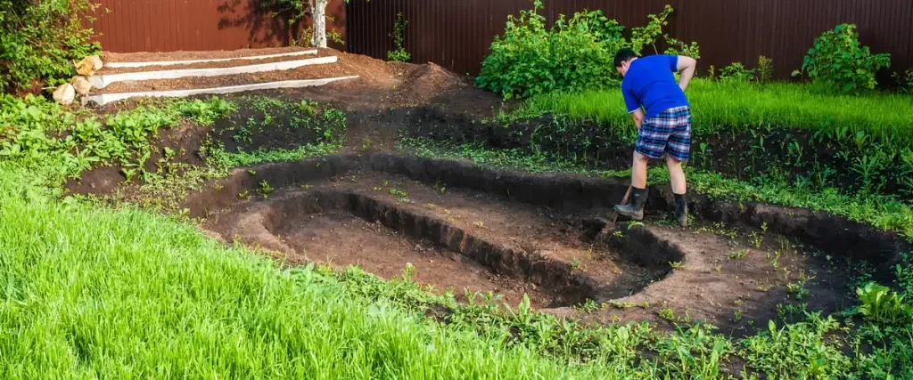 A backyard area being excavated and leveled in preparation for a new pond.